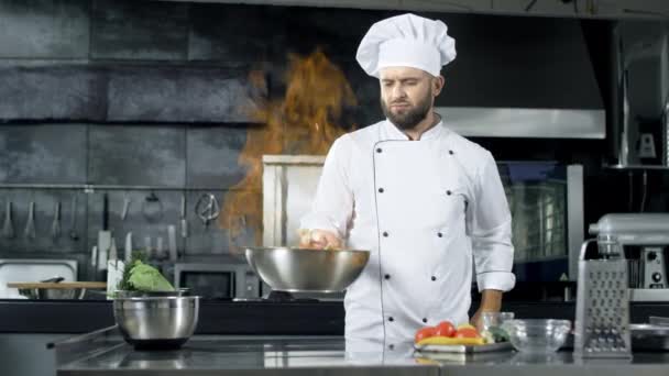 Professionele chef-kok gooien voedsel in pan met brandende vlam in de keuken - Video
