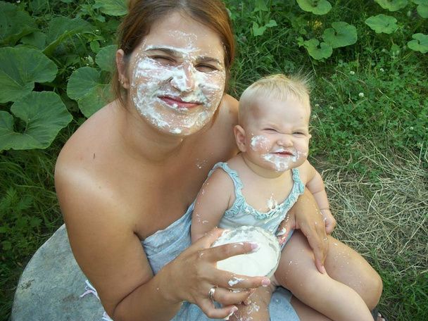 Mother with daughter making face masks using sour cream - Foto, Imagen