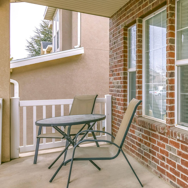 Καθαρίστε τετράγωνη μπροστινή βεράντα ενός σπιτιού με τραπέζι και καρέκλες μπροστά από τοίχο και παράθυρο - Φωτογραφία, εικόνα