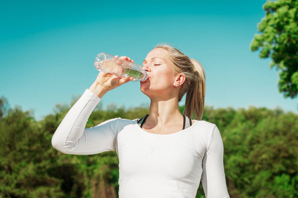 Loira, poderoso ajuste, mulher desportiva beber água após o seu treinamento
 - Foto, Imagem