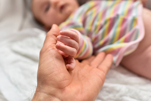 Pai segurando a mão de sua filha recém-nascida
. - Foto, Imagem