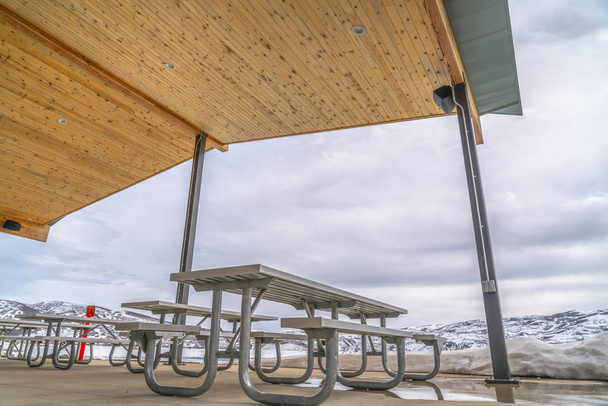 Mesas brancas e bancos dentro de um pavilhão cercado de neve no inverno
 - Foto, Imagem