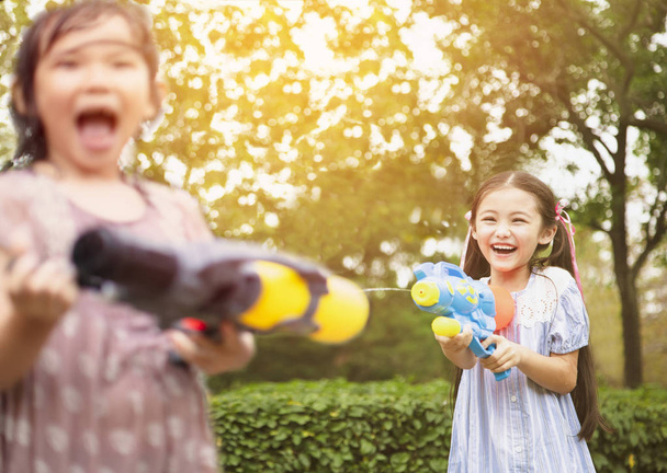 Счастливые девчонки играют в водяные пистолеты в парке
 - Фото, изображение