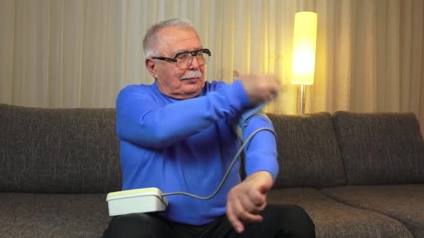 old man sitting on sofa enjoys measured good pressure - Filmati, video