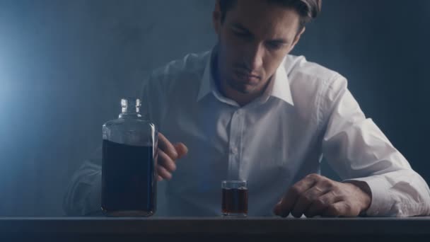 Un homme d'affaires déprimé verse du whisky dans un verre à boire seul dans une pièce sombre. Concept d'alcoolisme
. - Séquence, vidéo