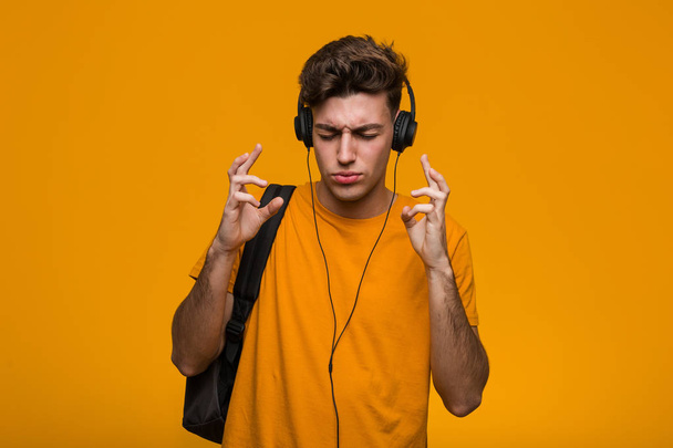 Jong cool student man luisteren naar muziek met koptelefoon wordt geschokt, ze heeft onthouden belangrijke vergadering. - Foto, afbeelding