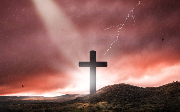 Silueta krucifix kříže při západu slunce se svěcenou světlem a pozadím s bouřkou. - Fotografie, Obrázek