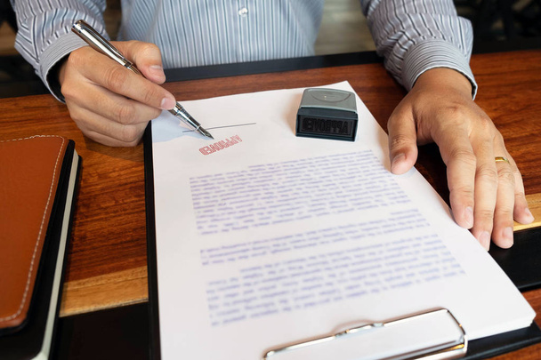 Крупным планом фотографии рук бизнесменов, подписывающих и штампующих в утвержденных контрактных бланках
 - Фото, изображение