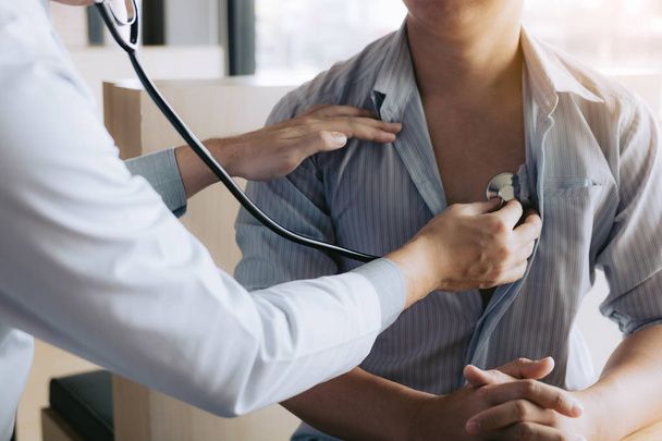 Aziatische arts is met behulp van een stethoscoop luisteren naar de hartslag van t - Foto, afbeelding