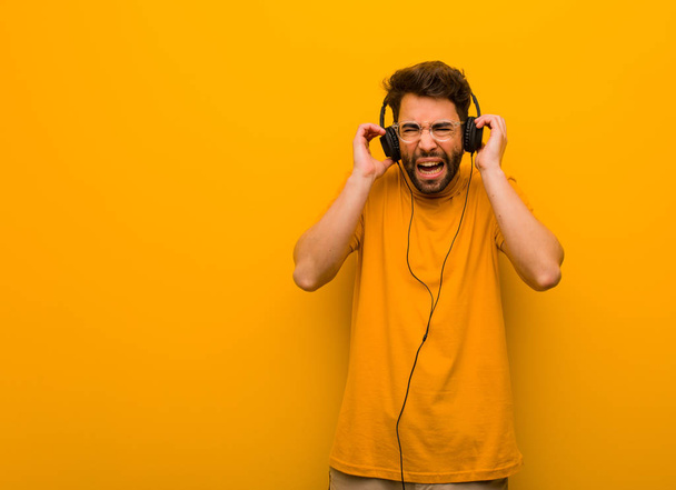 Νεαρός που ακούει μουσική και καλύπτει τα αυτιά με τα χέρια - Φωτογραφία, εικόνα