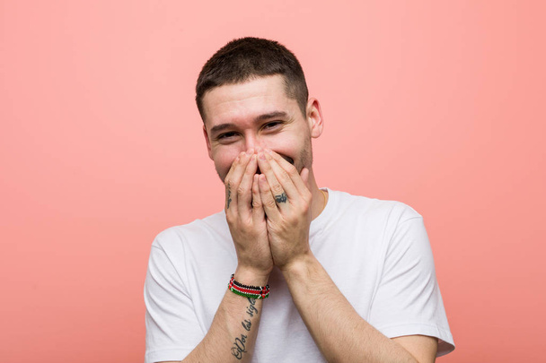 Young casual man laughing about something, covering mouth with hands. - Photo, Image