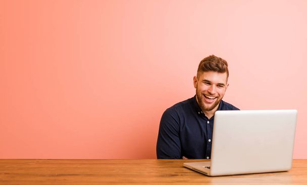 Jeune homme travaillant avec son ordinateur portable rire et s'amuser
. - Photo, image