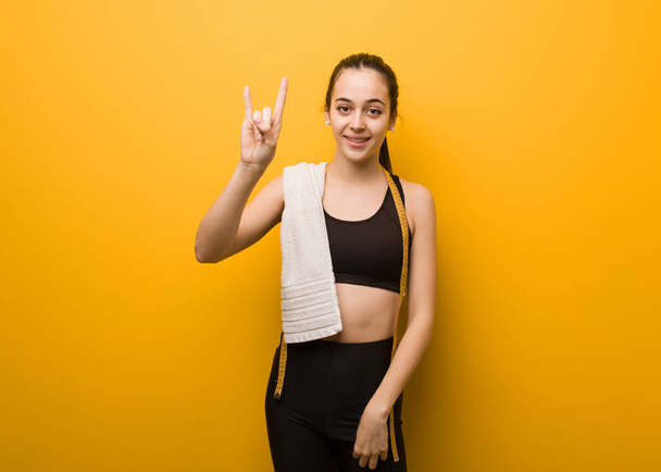 junges Fitness-Girl macht eine Rock-Geste - Foto, Bild