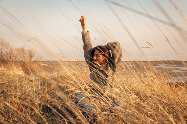 Plenerowa Fotografia mody młodej pięknej kobiety w brązowym swetrze i jeansach w krajobrazie jesiennym. Lookbook mody.  - Zdjęcie, obraz