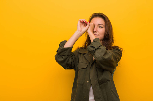 Young european woman isolated over yellow background looking far away keeping her hand on forehead. - Photo, image