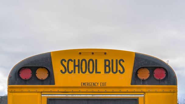 Clear Panorama Traseira de um ônibus escolar amarelo com luzes de sinal e janela de saída de emergência
 - Foto, Imagem