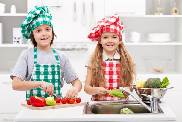 kinderen helpen in de keuken - wassen en snijden van groenten - Foto, afbeelding