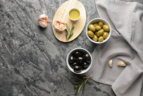 Tasty oil with olives and garlic on grey table - Zdjęcie, obraz