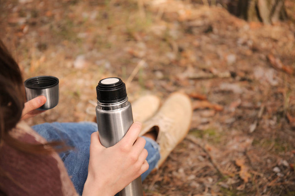 Donna che beve tè caldo dal thermos nella foresta
 - Foto, immagini