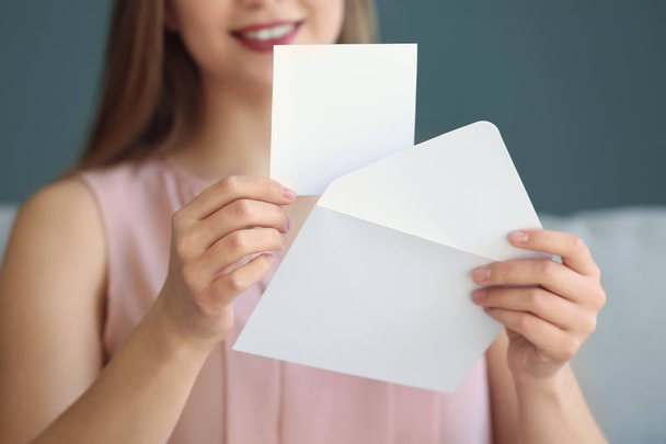 Young woman opening envelope with invitation at home, closeup - Фото, изображение