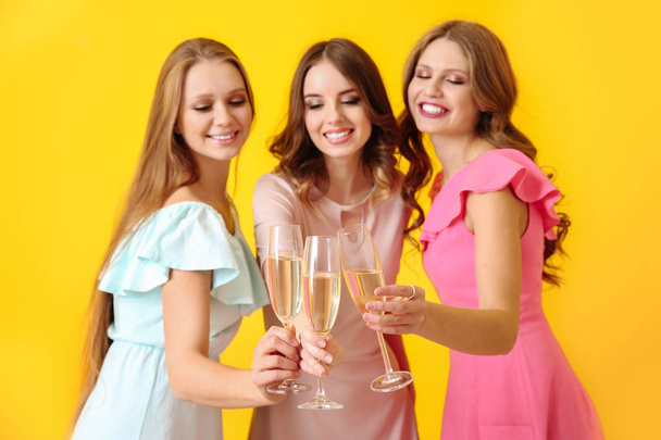 Beautiful young women drinking champagne on color background - Photo, Image