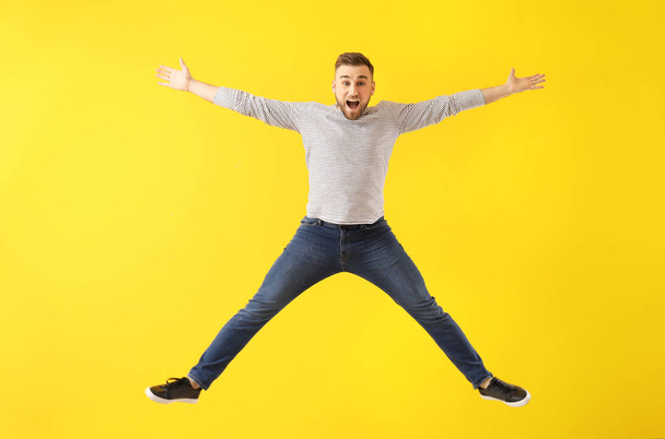 Jumping young man on color background - Fotoğraf, Görsel