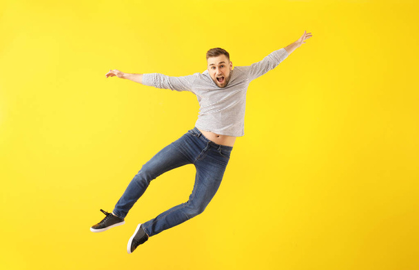 Springender junger Mann auf farbigem Hintergrund - Foto, Bild