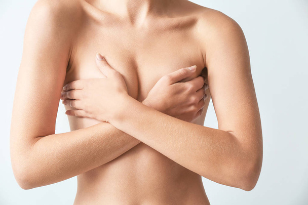 Naked woman on light background. Concept of breast augmentation - Foto, Bild