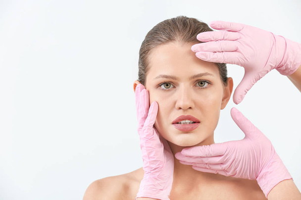 Chirurghi plastici toccare volto di giovane donna su sfondo chiaro
 - Foto, immagini