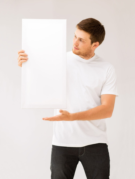 Young man holding white blank board - Фото, изображение