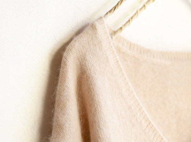 light pink sweater hanging on clothes hanger on white background. - Фото, зображення