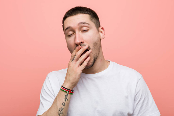 Young casual man yawning showing a tired gesture covering mouth with him hand. - Photo, Image