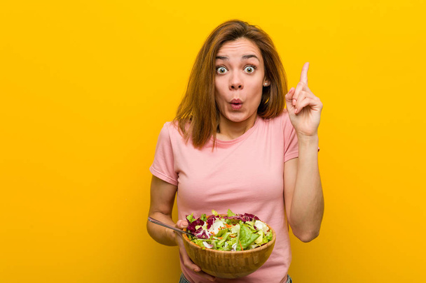 Jeune femme en bonne santé tenant une salade ayant une bonne idée, concept de créativité
. - Photo, image
