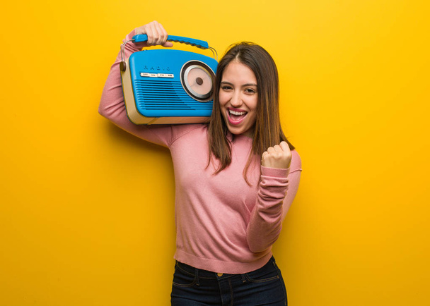 Νεαρή χαριτωμένη γυναίκα κρατώντας ένα vintage ραδιόφωνο έκπληκτος και σοκαρισμένος - Φωτογραφία, εικόνα