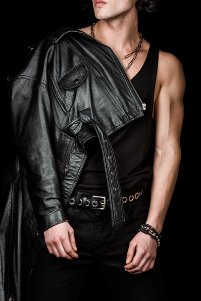cropped view of confident man in leather jacket standing isolated on black  - Foto, afbeelding