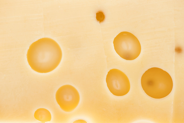 close up view of textured yellow cheese with wholes - Foto, Imagen