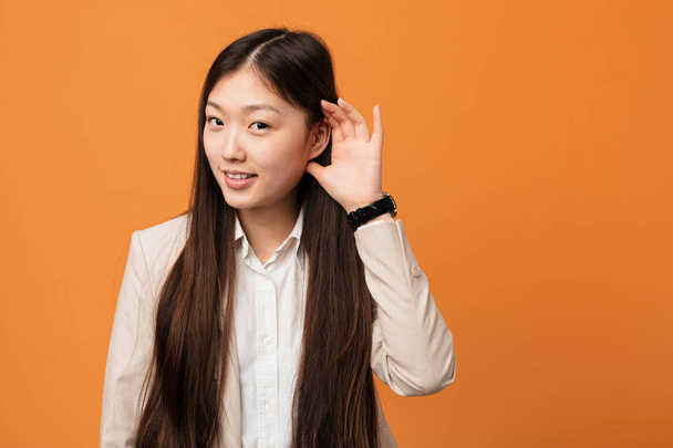 Fiatal üzleti kínai nő próbál hallgatni egy pletykát. - Fotó, kép