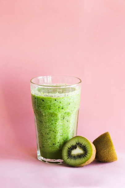Healthy green smoothie in a glass cup on pink background - Foto, afbeelding