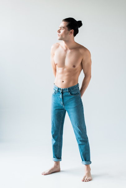 handsome shirtless man standing in blue jeans on white  - 写真・画像