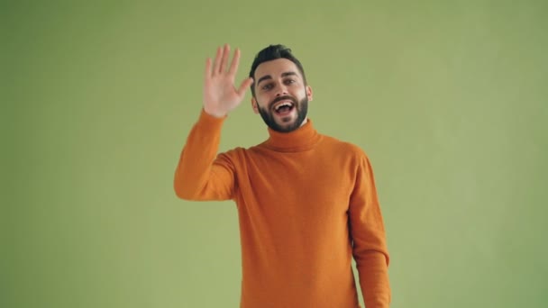 Portrait of handsome student waving hello then showing come here gesture - Filmagem, Vídeo