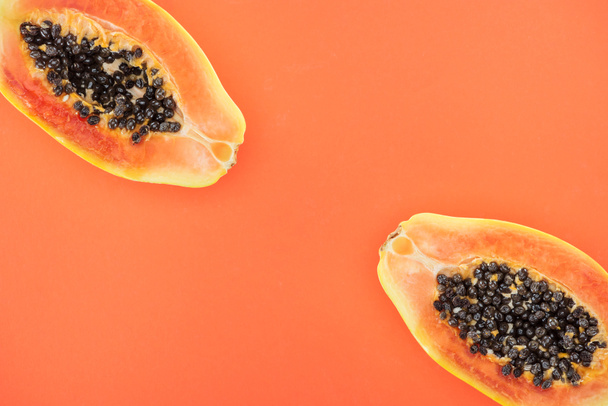 top view of exotic papaya halves with black seeds isolated on orange - Foto, afbeelding