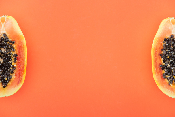 Widok z góry z dojrzałych połówek papai z czarnymi nasionami na pomarańczowo - Zdjęcie, obraz