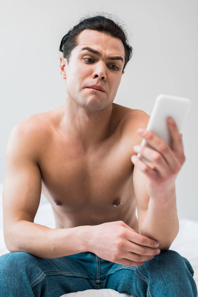 evde akıllı telefon bakarak gömleksiz adam seçici odak  - Fotoğraf, Görsel