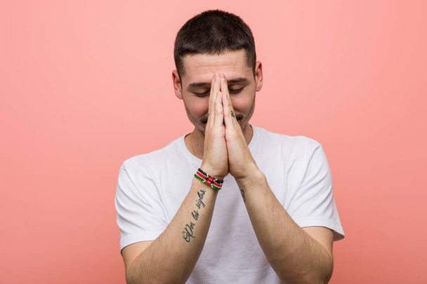 Mladý ležérní muž drží ruce v modlitbě blízko úst, cítí sebevědomí. - Fotografie, Obrázek