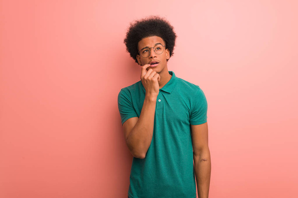 Mladý Afričan americký muž na růžové zdi pochybovělé a zmatené - Fotografie, Obrázek
