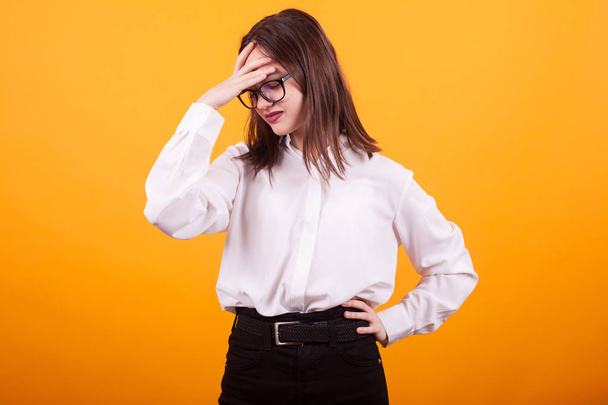 Beautiful teenage girl having a migraine in studio over yellow background - Fotografie, Obrázek