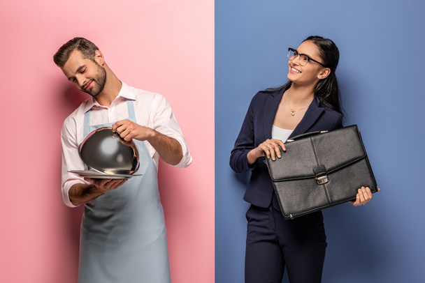 homme en tablier avec plateau de service et femme d'affaires souriante avec mallette sur bleu et rose
 - Photo, image