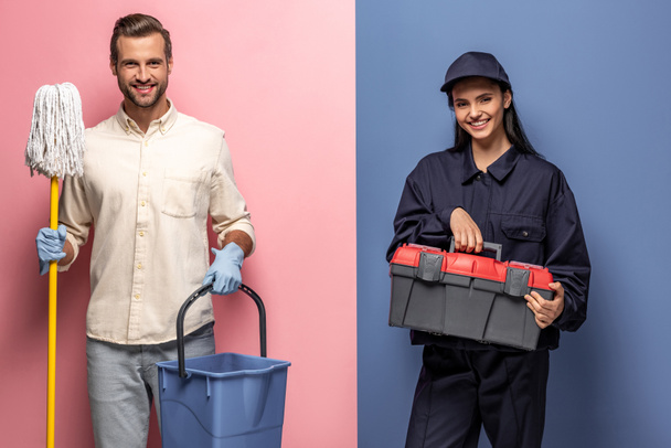 man in rubber gloves with mop and woman in construction worker uniform with tool box looking at camera on blue and pink - Photo, Image