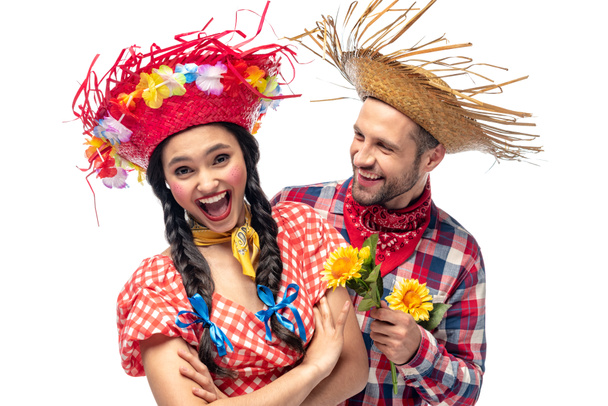 man en opgewonden jonge vrouw in feestelijke kleren met zonnebloemen geïsoleerd op wit - Foto, afbeelding