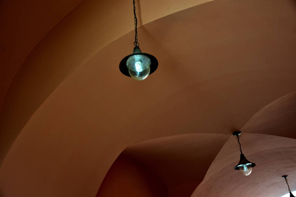 Два лампи вінтажного стилю висять на ланцюгах на стелі зі склепінчастою терасою
 - Фото, зображення
